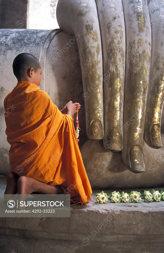 Thailand, Sukhothai, novice monk praying Buddah at Temple Wat Sri Chum