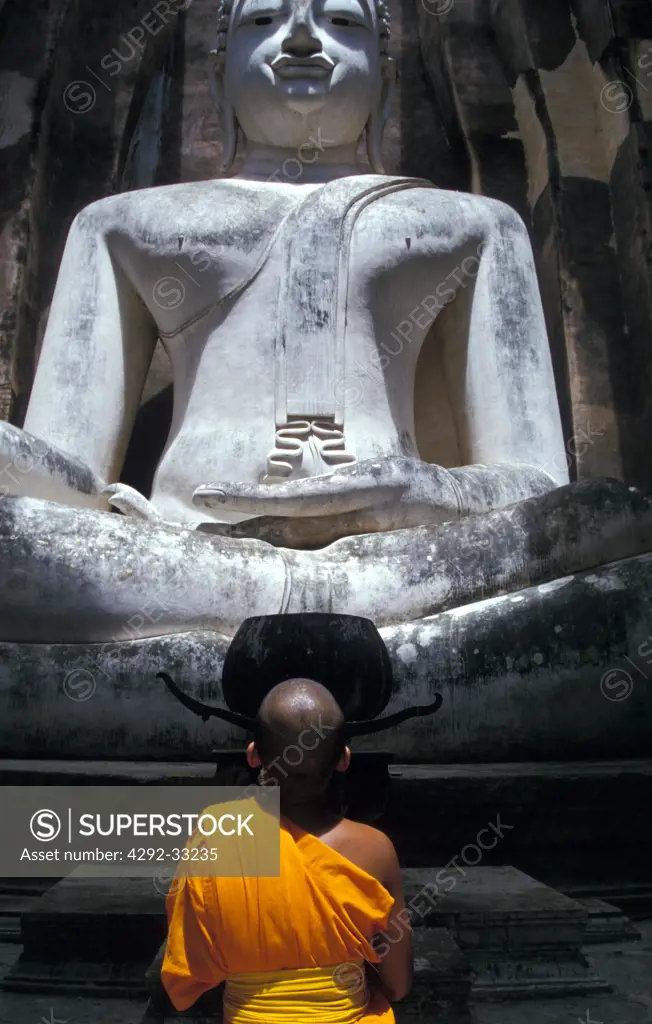 Thailand, Sukhothai, novice monk praying buddha at temple Wat Sri Chum