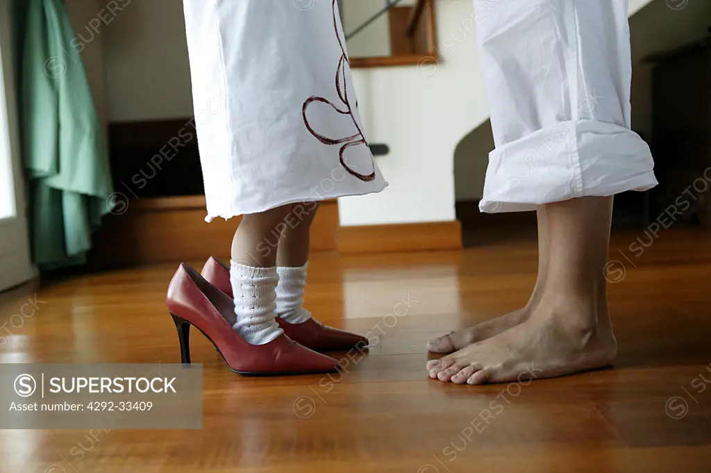 Mother barefoot and daughter with high-heeled shoes