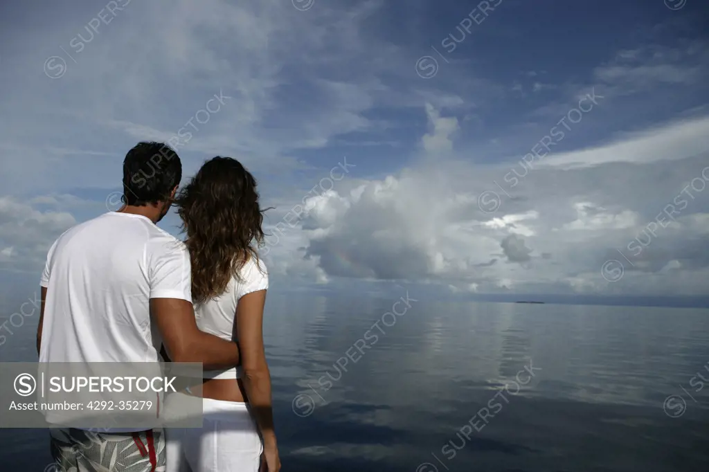 Couple at sea looking at horizon, Maldives