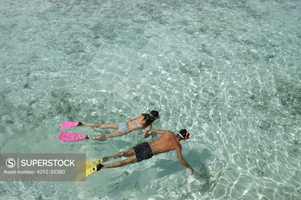Couple snorkeling in transparent water