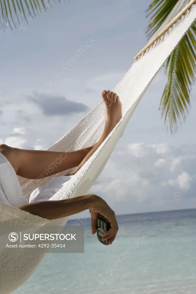 Woman in hammock holding mobile, legs detail