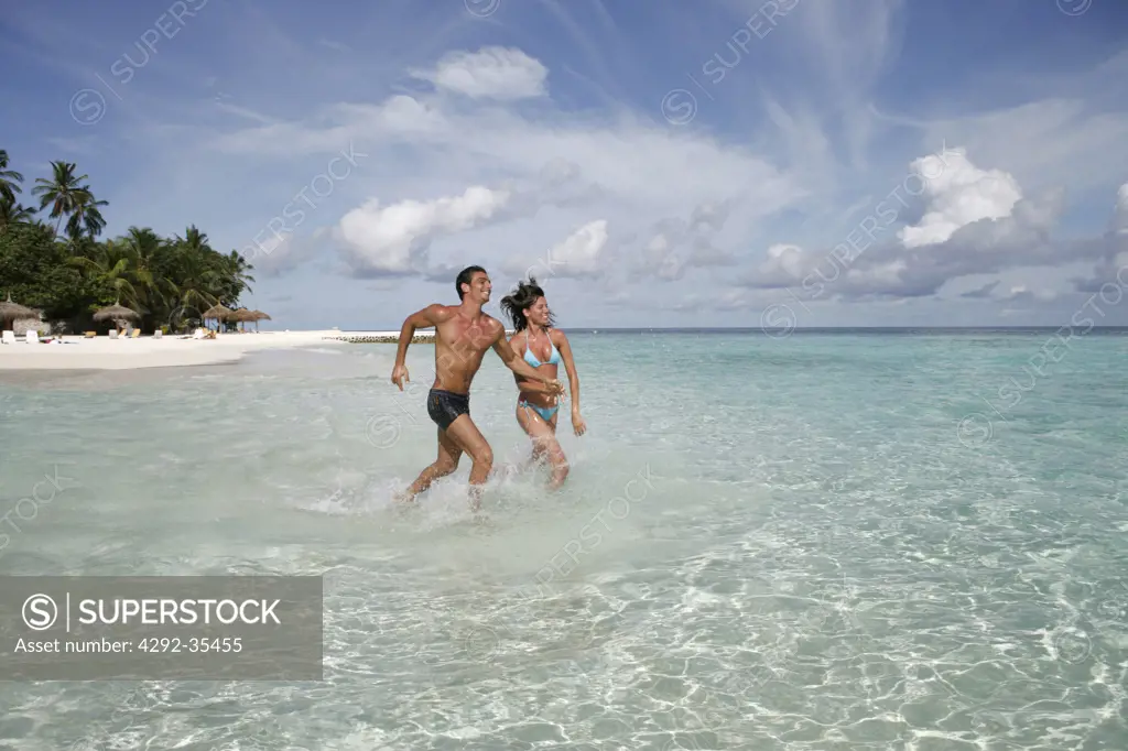 Couple at sea running in shallow water