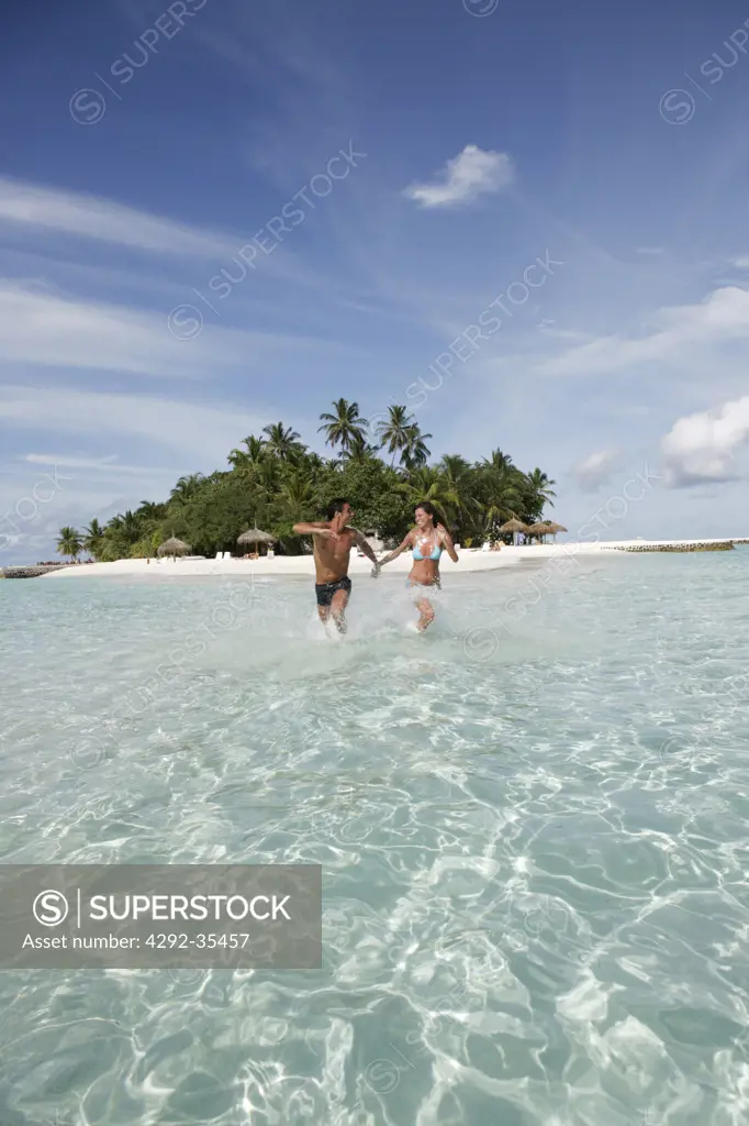 Couple at sea running in shallow water