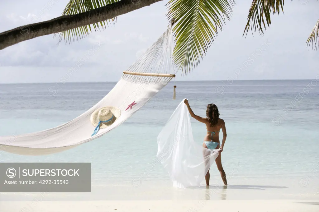 Woman with pareu standing by hammock