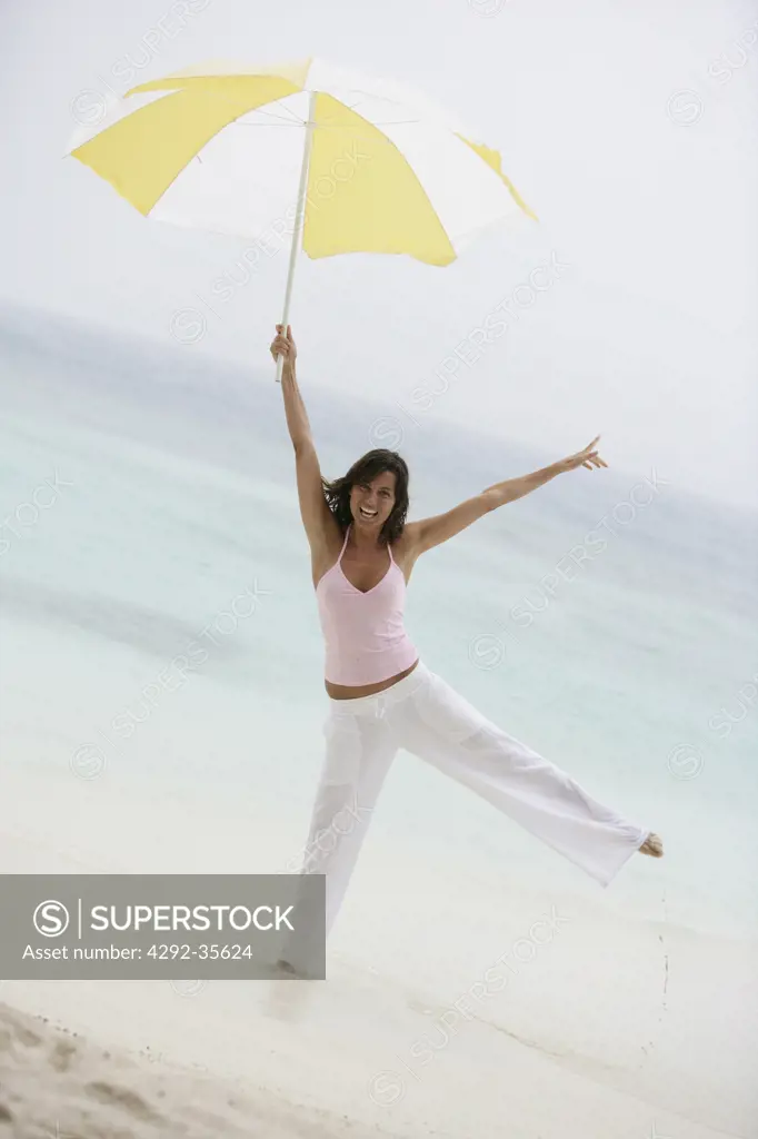 Playful woman on the beach holding parasol