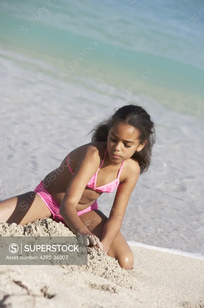 Girl on the beach playing with sand
