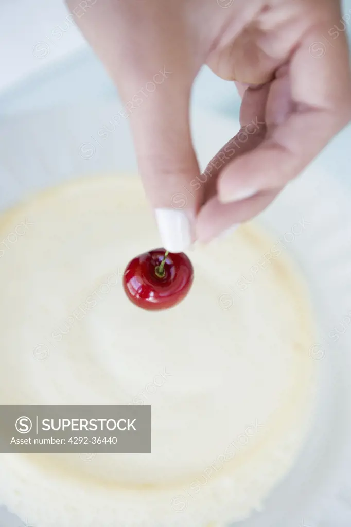 Woman putting cherry on the cake