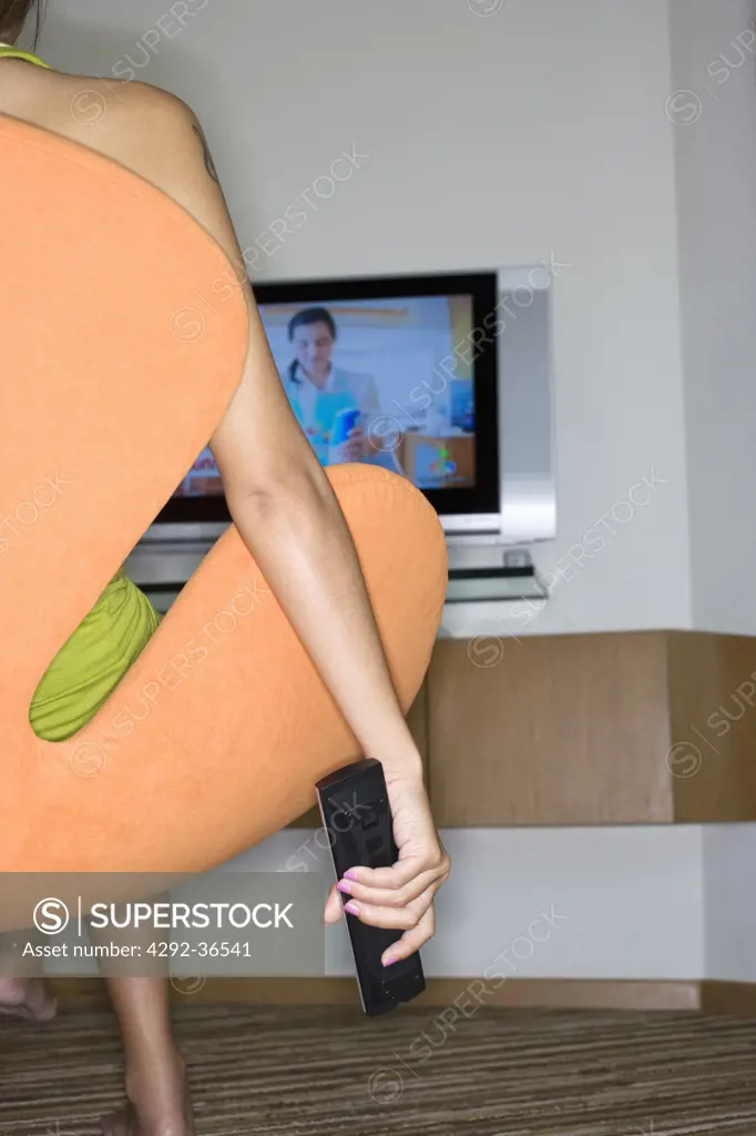 Woman sitting in arm chair, channel surfing