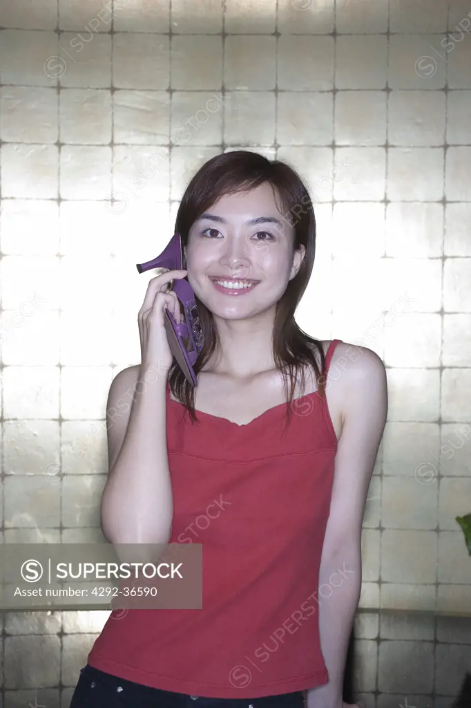 Chinese woman holding high heel sandal on her ear