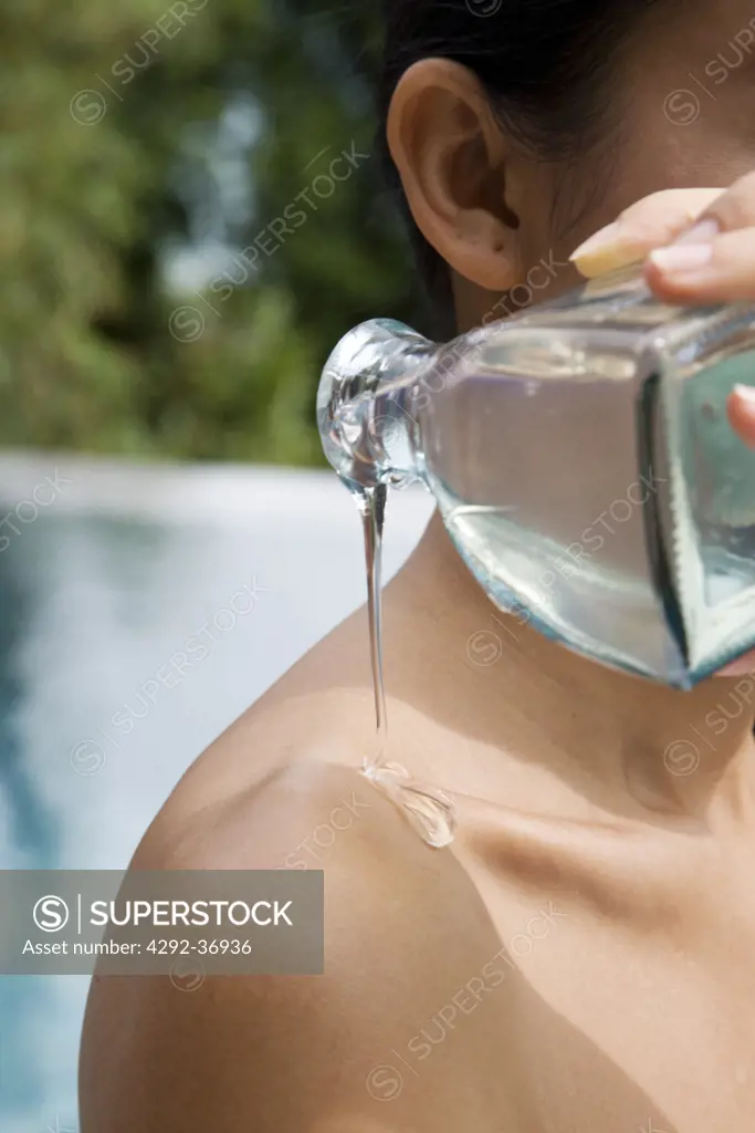 Woman pouring essential oil on her shoulder