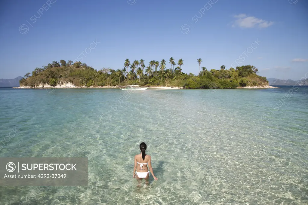 Philippines, El Nido bay,Snake Island,rear view of a woman at sea standing in shallow water.