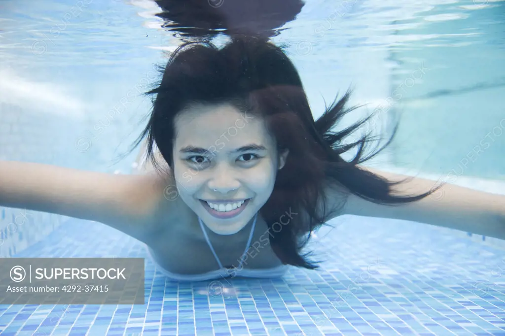 Underwater view of a woman in swimming pool at Dhevi Mandarin Oriental resort, Chiang Mai, Thailand