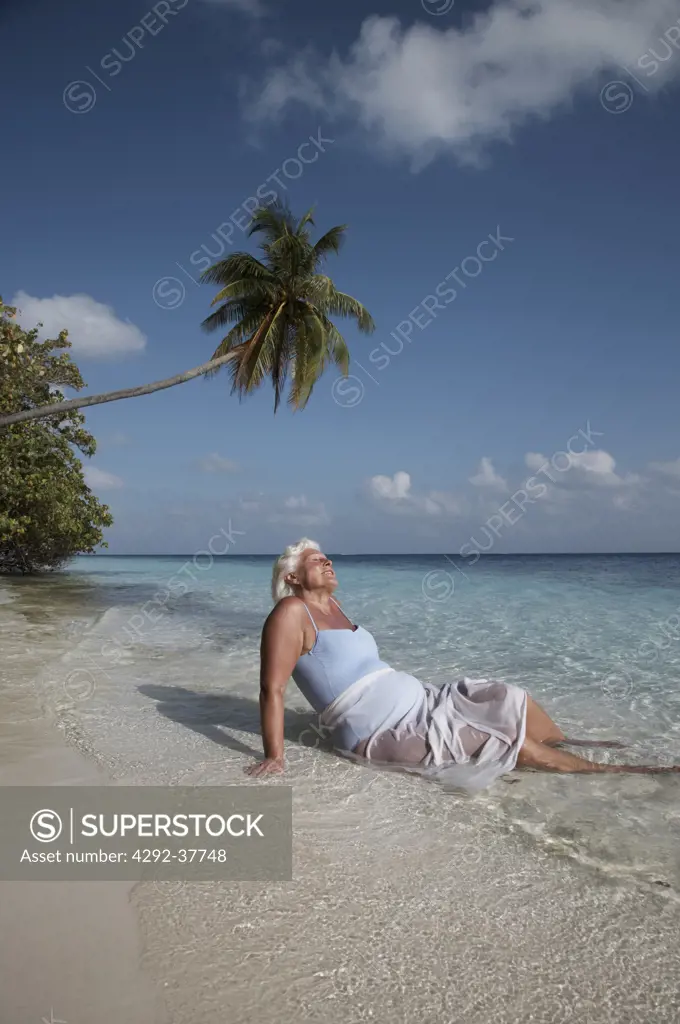 Maldives, Ari Atoll, senior woman relaxing on the beach