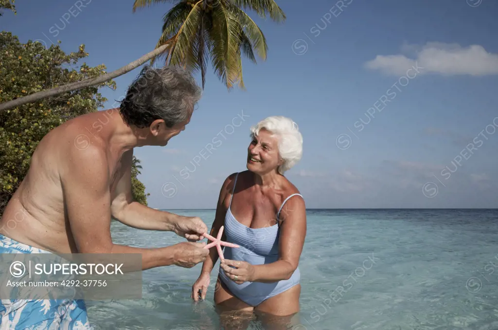 Maldives, Ari Atoll, senior couple holding a starfish