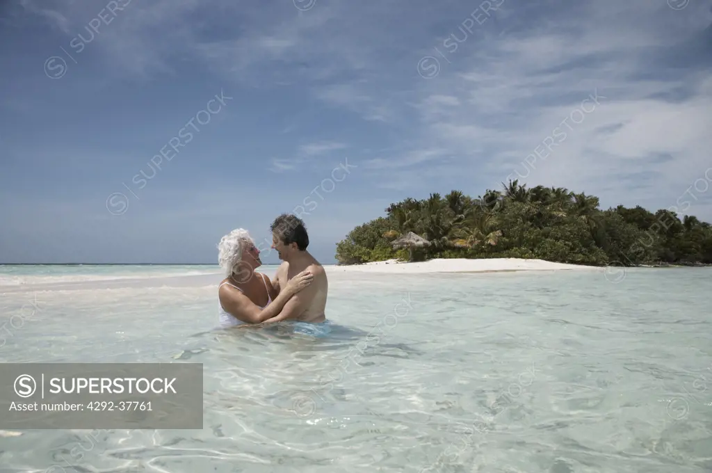 Maldives, Ari Atoll, senior couple embracing in the sea