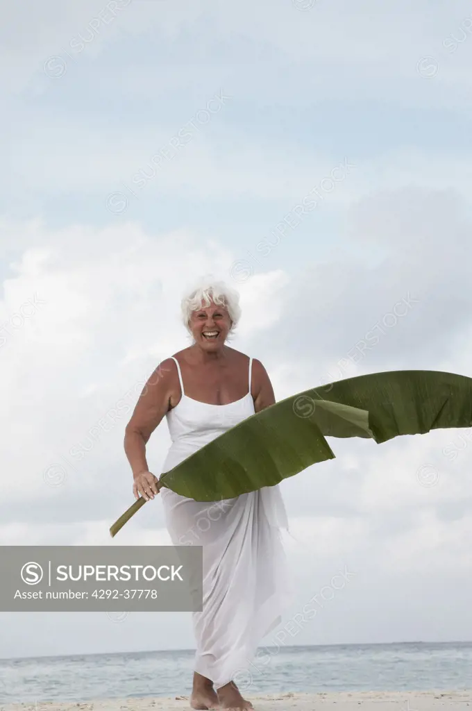 Maldives, Ari Atoll, senior woman holding a leaf