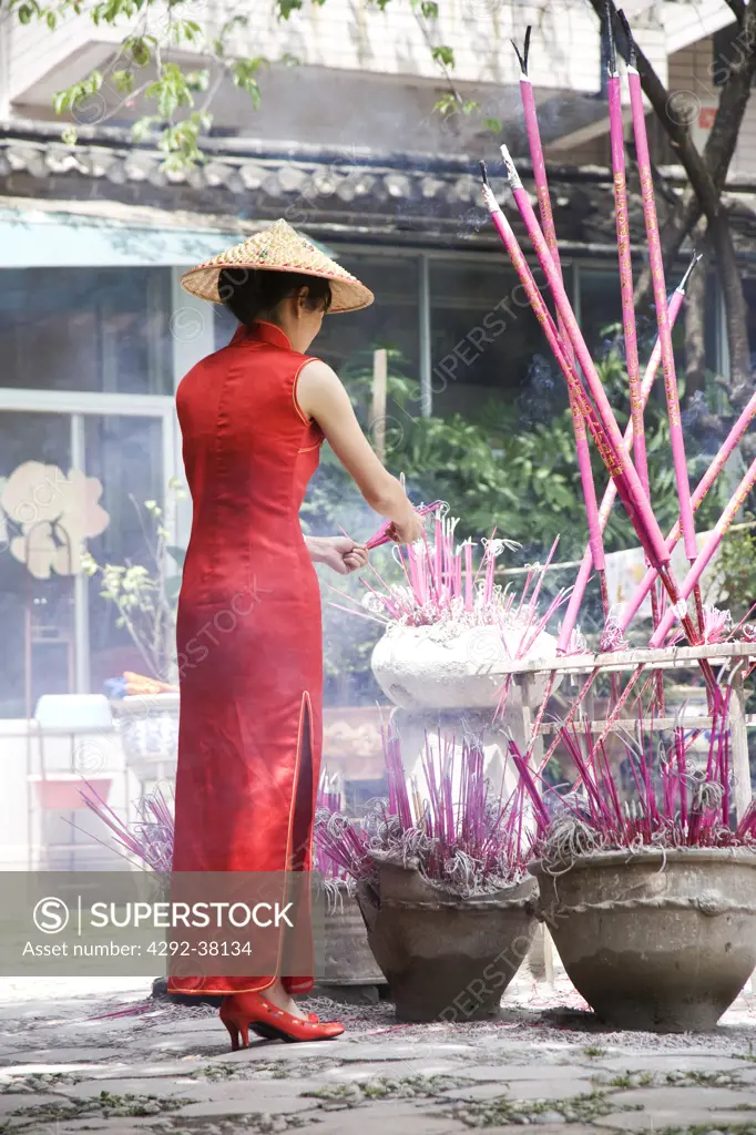 China, Yunnan province, Shangri-La region, Lijiang. Woman wearing traditional chinese clothing burning incense