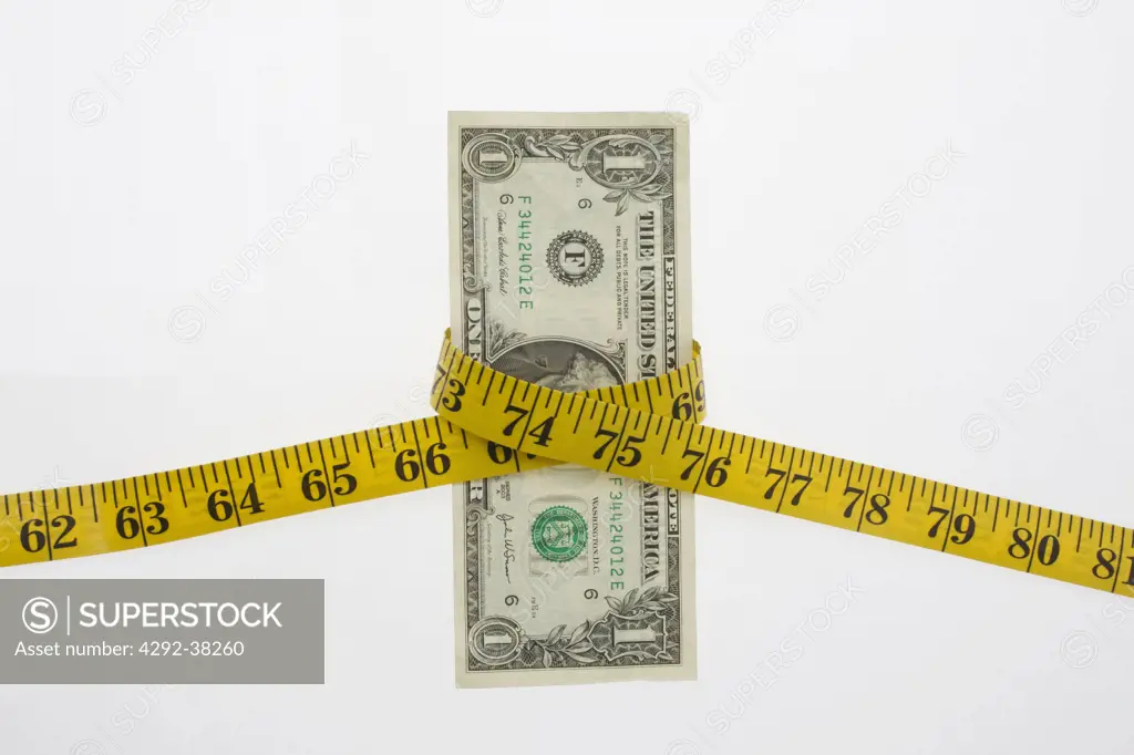 Dollar banknotes wrapped in measuring tape