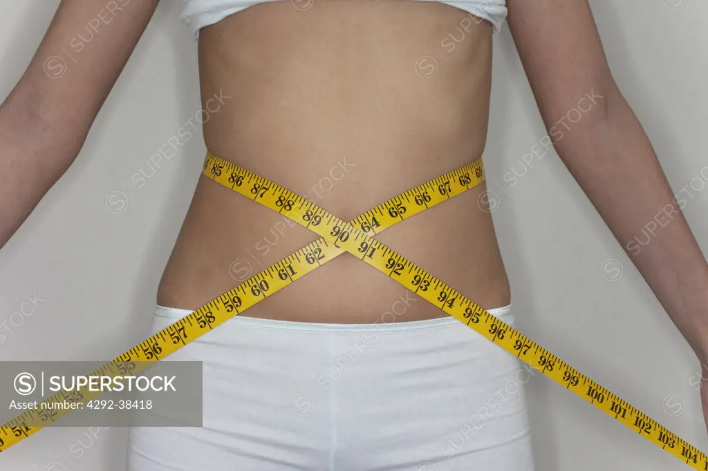 Woman measuring her waist with a tape measure