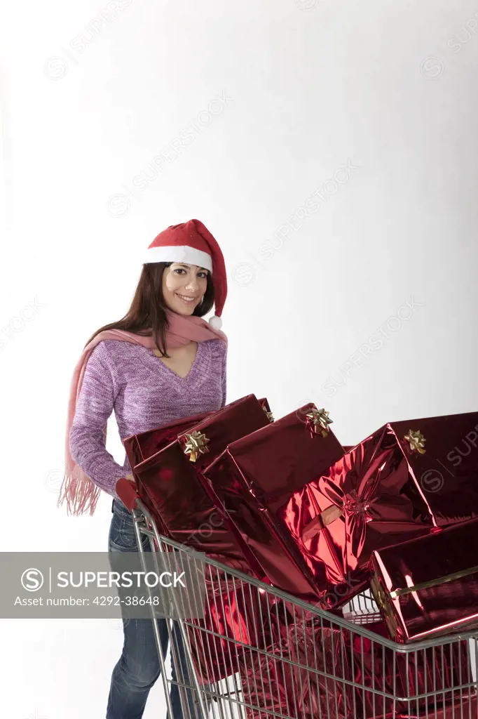 Portrait of woman with shopping cart fullof christmas gifts