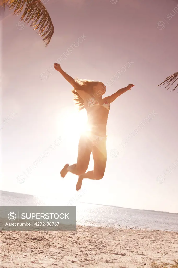 Woman jumping in the air at the beach