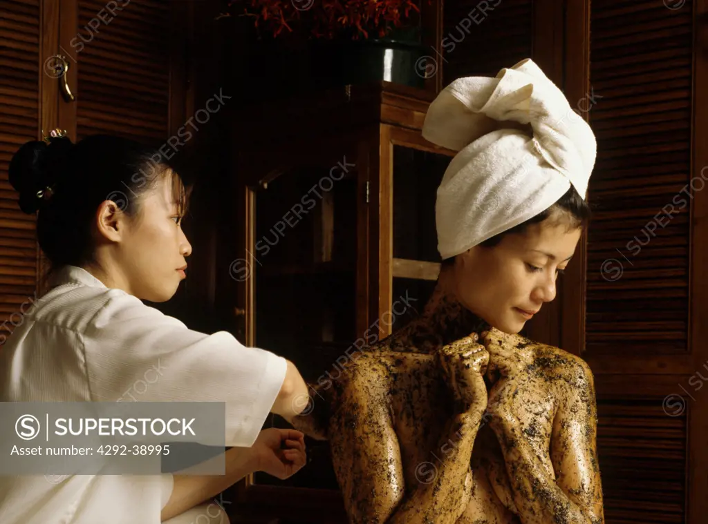 Woman applying body mud mask. Thailand, Bangkok, Oriental Hotel Spa