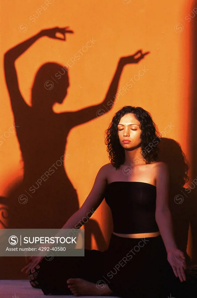 Woman and shadow of a woman practising yoga