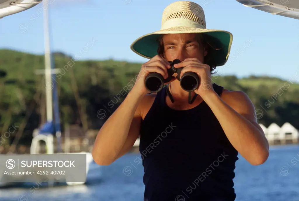 Australia, Queensland, Whitsunday Islands, Man with binoculars on a boat in front of Lindeman island
