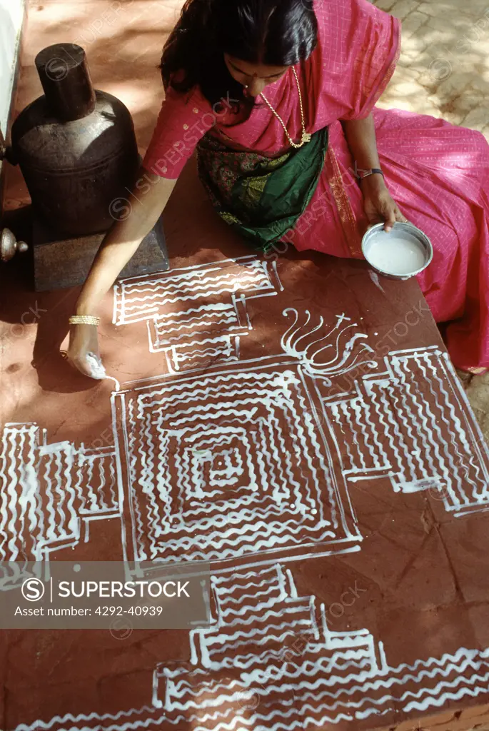 India, Tamil Nadu, woman drawing 'rangoli' auspicius design in from of house