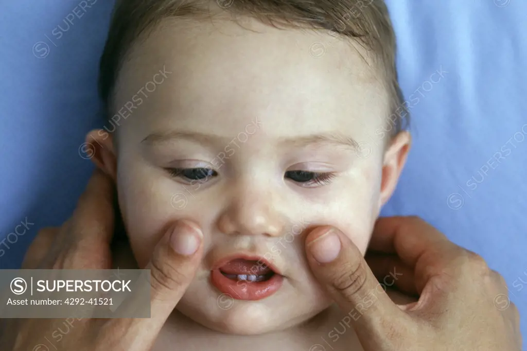 Fingers massaging baby's face
