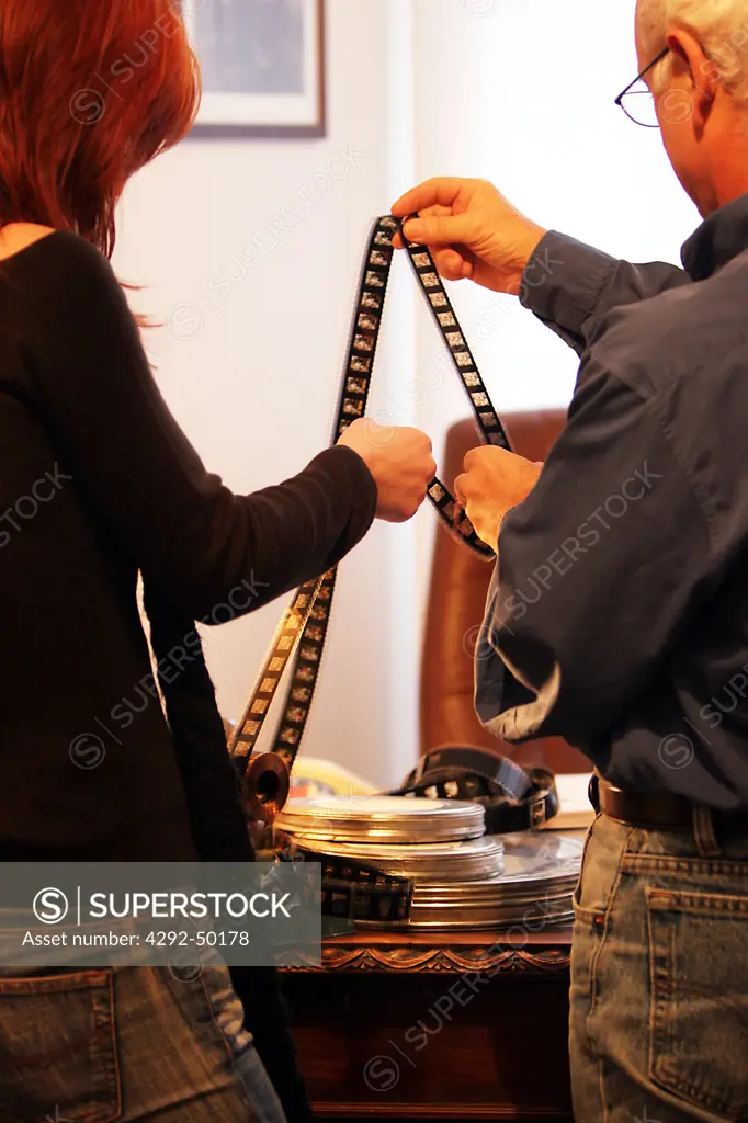 Man and woman at office looking at film reel