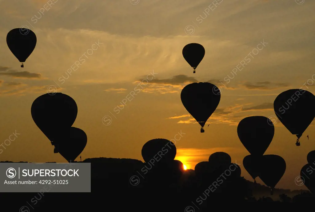 Silhouette of hot air balloons during race at sunset