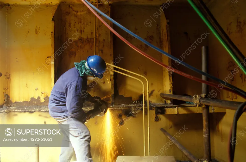 Welder at work in ship's hull