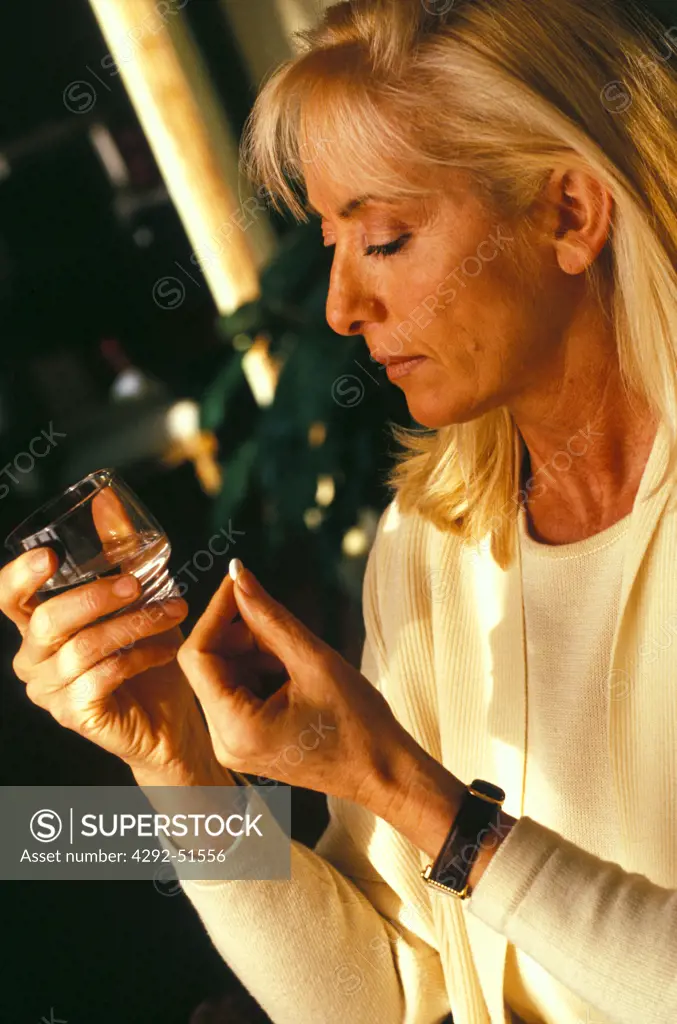 Woman with a pill and a glass of water in her hands