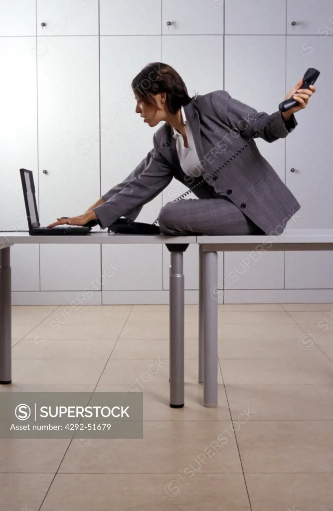 Woman in office working with laptop and phoning