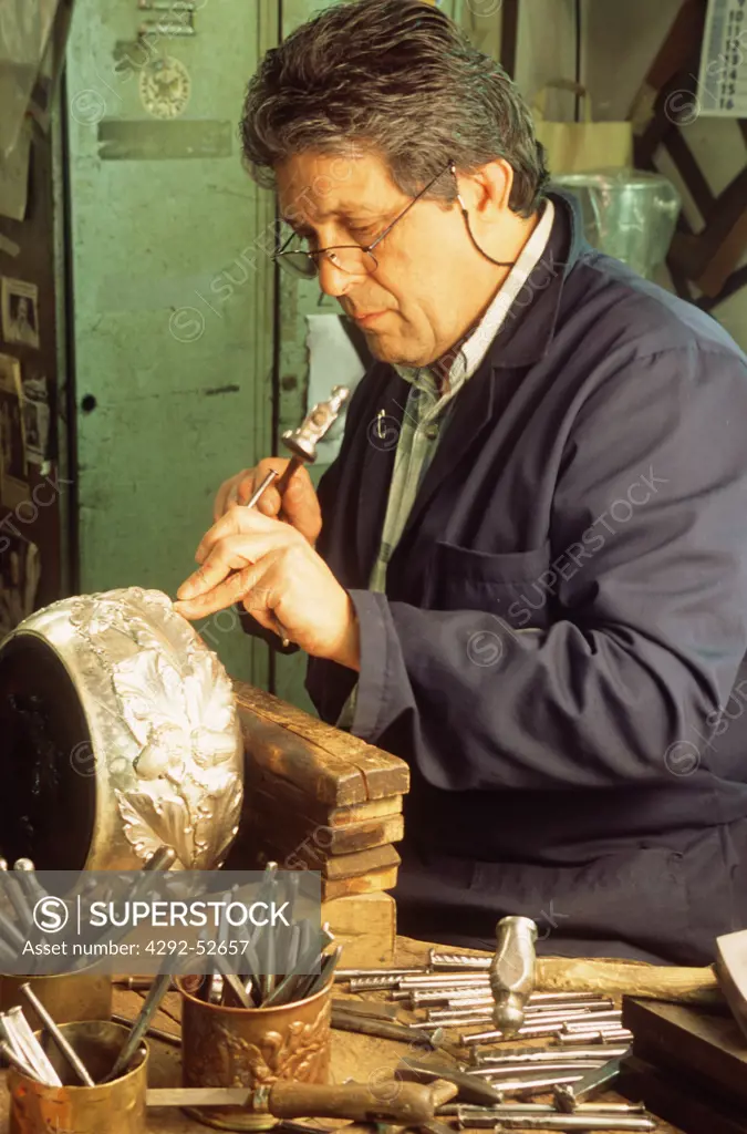 Italy, Tuscany. Crafstman hammering an handmade silver bowl