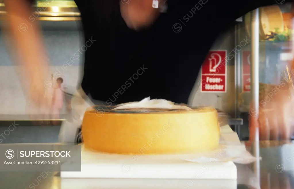 Woman cutting Bregezelwalder cheese, Lingenau, Vorarlberg, Austria