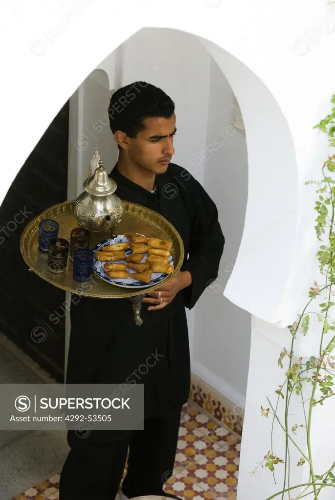 Morocco, Marrakech, hotel waiter serving tea with briouats