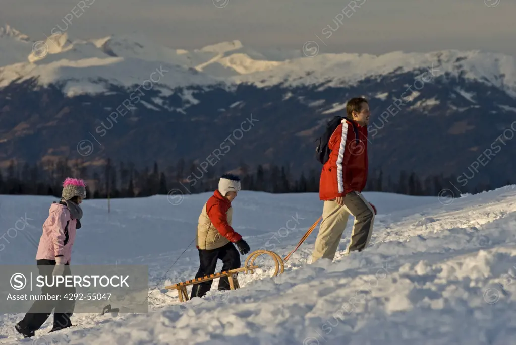 Austria, Carinthia, Villach, Dobratsch Natural Park, Father pulling sleds
