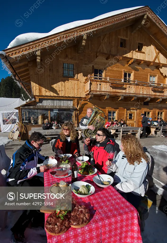 Italy, Trentino Alto Adige, Val di Funes, people having lunch with musician