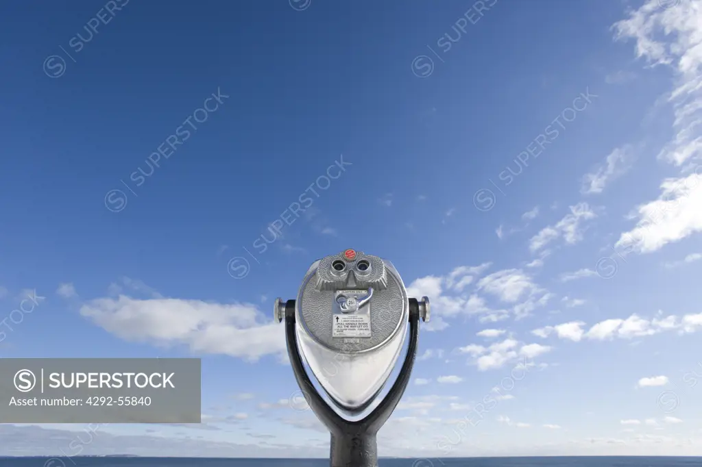 Binoculars focused on the horizon on a blue sky with passing white clouds. Pemaquid Point. Bristol, Maine