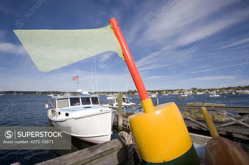 Flag on a lobster buoy and a boat at a dock in Boothbay harbor, Maine.