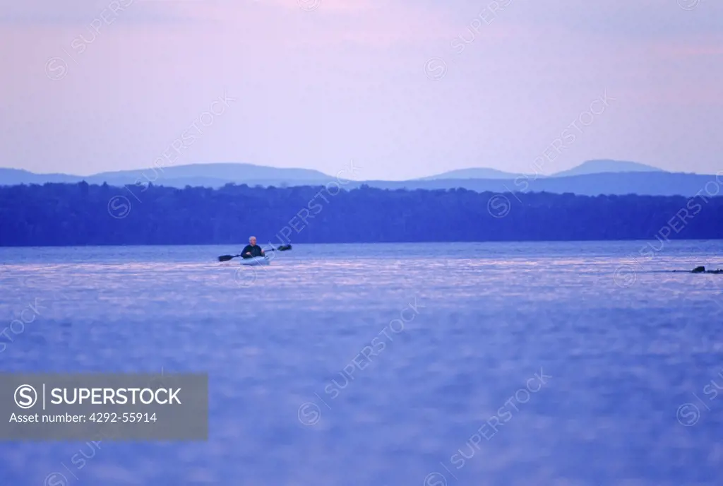 Man in a kayak on a lake at sunset