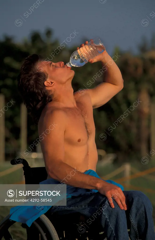 Disabled man in wheelchair drinking from bottle of water