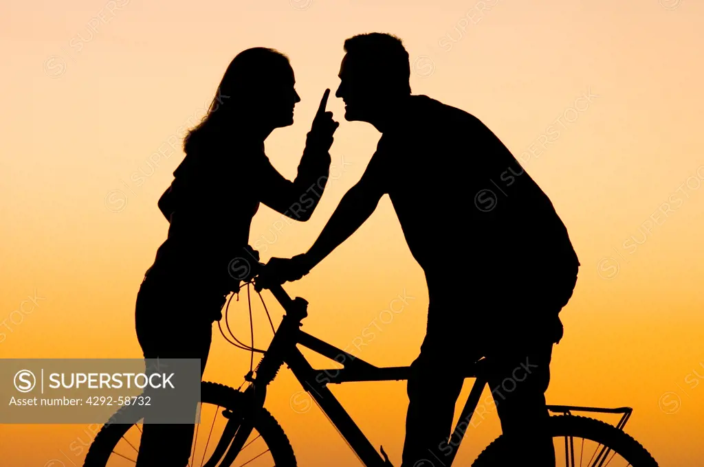 Teenage couple at the beach with bicycle at sunset
