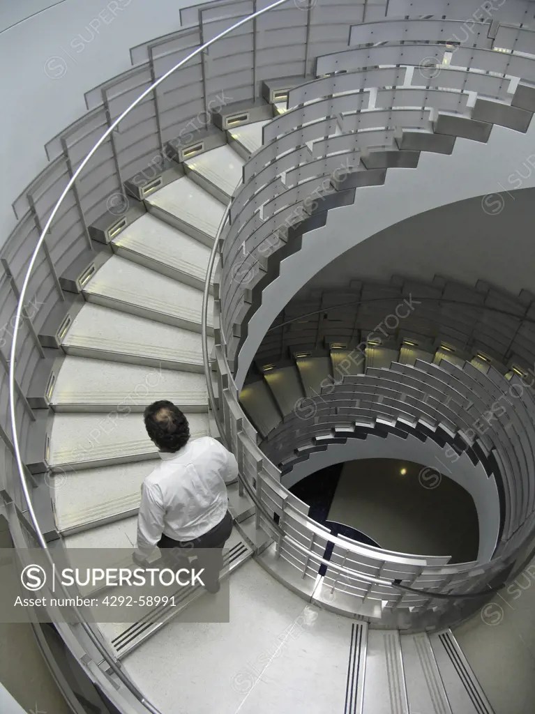 View from above of man in white shirt walking up circular staircase