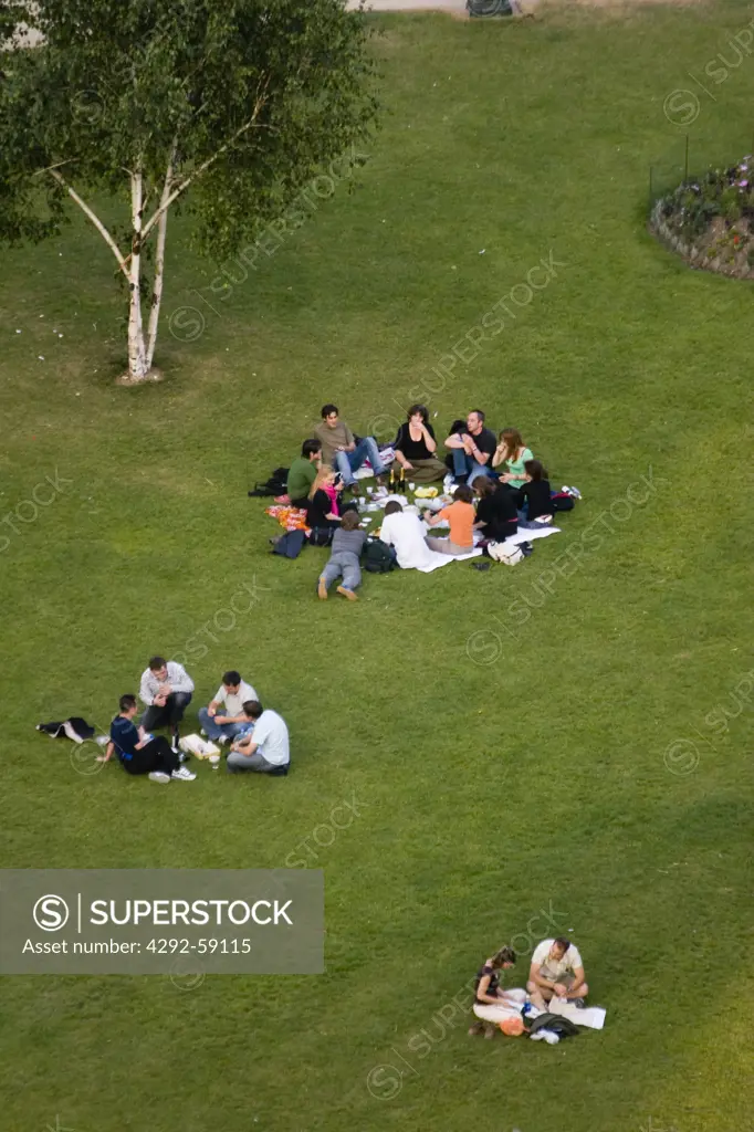 People picnicking on grass under the Eiffel Tower, Paris, France
