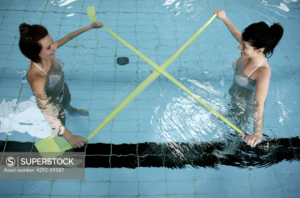 Women in swimming pool doing pilates exercise