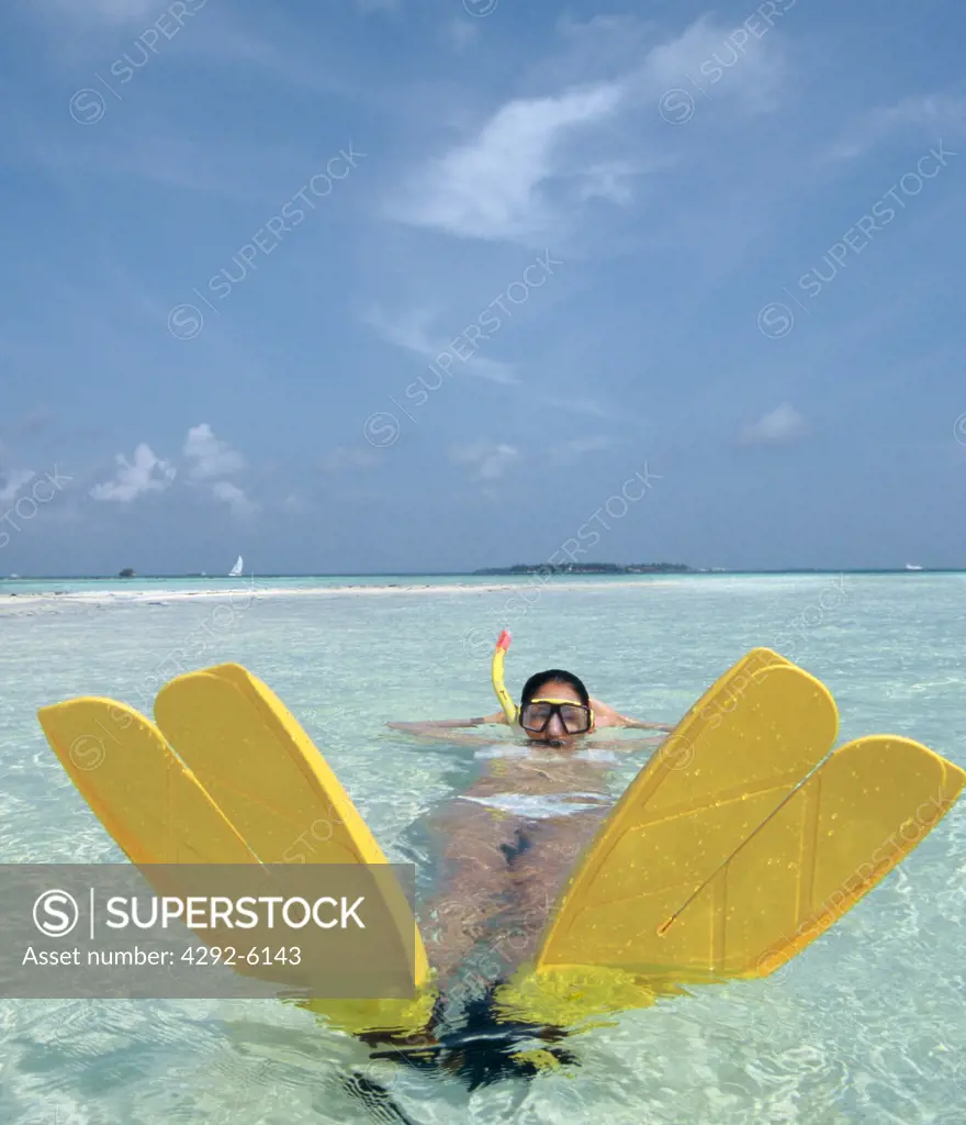 Maldives, woman with flippers and scuba mask lying in shallow water
